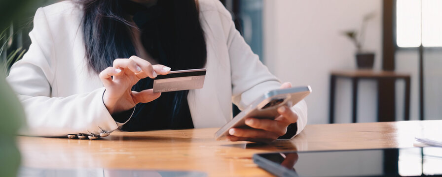 A wonan holding credit card and typing in credit card number smartphone for online shopping and payment makes a purchase on the Internet.