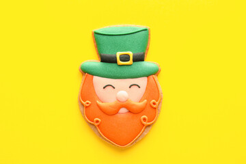 Tasty decorative gingerbread cookie for St. Patrick's Day celebration on yellow background