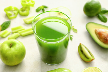 Glass of healthy green juice and fresh ingredients on light background