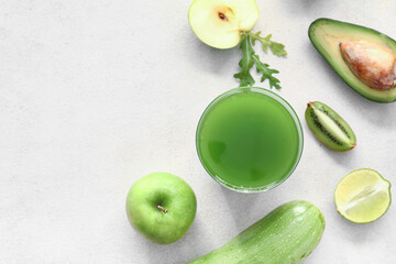 Glass of healthy green juice and fresh ingredients on light background
