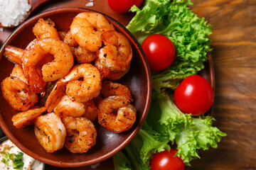 Plate of tasty shrimp tails and tomatoes on table
