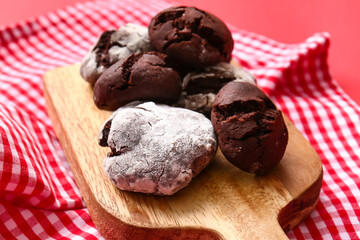 Board with tasty brownie cookies on red background