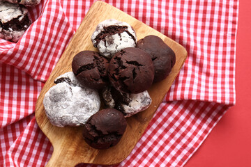 Board with tasty brownie cookies on red background