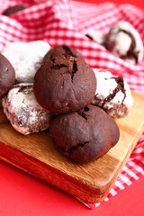 Board with tasty brownie cookies on red background