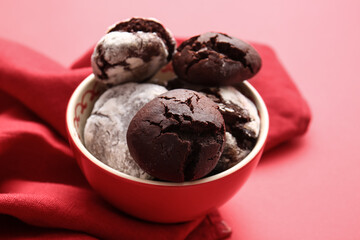 Bowl with tasty chocolate brownie cookies on red background