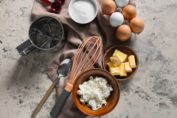 Bowl with cottage cheese and ingredients for preparing pancakes on beige background