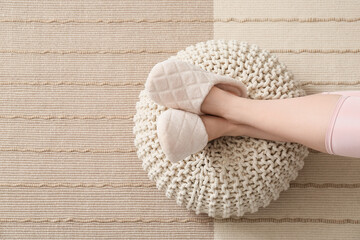 Woman resting on pouf at home, closeup