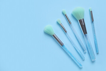 Different makeup brushes on blue background