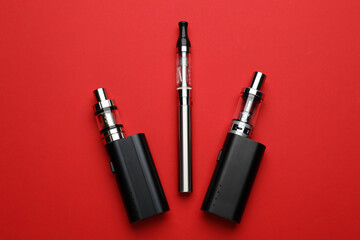 Electronic smoking devices on red background, flat lay
