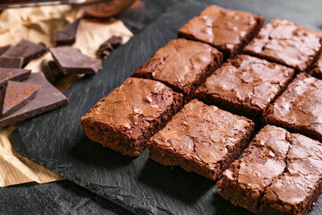 Board with pieces of tasty chocolate brownie on table, closeup