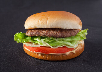 Hamburger with lettuce and tomato on a dark background