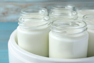Modern yogurt maker with full jars, closeup