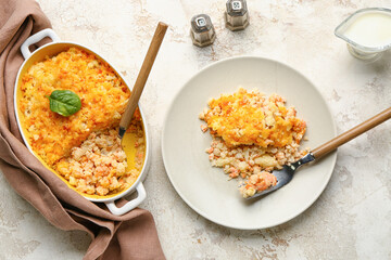 Plate and baking dish with tasty English fish pie on light background