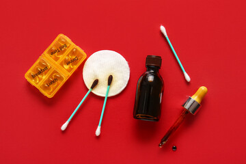 Bottle with iodine, cotton pads, swabs and organizer with pills on red background