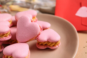 Plate with tasty heart shaped macaroons on table, closeup