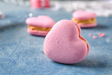 Tasty heart-shaped macaroon on blue background