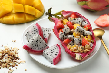 Yummy pitahaya boat with mango, granola and strawberry on white table