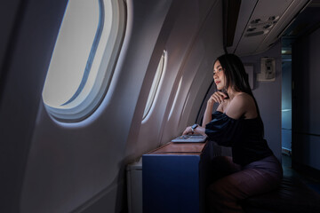 Beautiful asian woman tourist on first class passenger seat near window in airplane, travel and rest  on holidays.