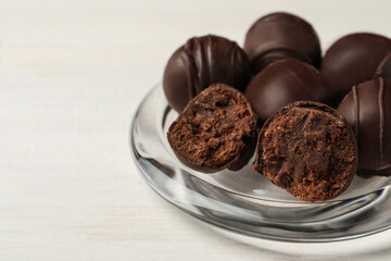 Many delicious chocolate truffles on white table, closeup. Space for text