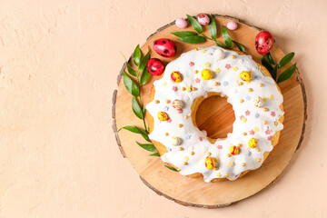 Wooden board with tasty Easter cake and eggs on beige background