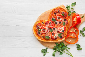 Board with tasty heart-shaped pizza on white wooden background. Valentine's Day celebration