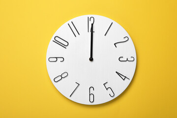 Modern clock on yellow background, top view