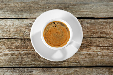 Cup of tasty coffee on wooden table, top view