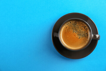 Cup of tasty coffee on light blue background, top view. Space for text