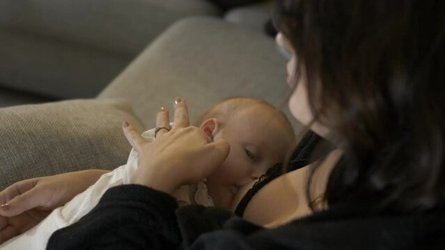 Mother breastfeeding cute newborn baby, close over the shoulder view