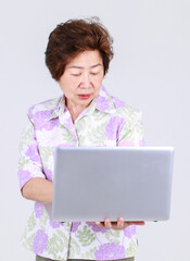 Senior Asian aunt as elderly teacher playing business laptop to explain sale promotion and public...