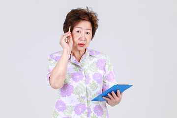 Elderly aunt, Senior Asian woman elderly teacher recording creative idea by writing a memo on note...