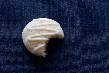 A fresh homemade lemon sugar cookies with drizzled icing and bite taken; Pretty white cookie with...