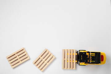 Toy forklift and wooden pallets on white background, top view © New Africa