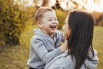 Portrait of a boy happily spending time with his mother in the park. Modern lifestyle. Family care. Smiling happy child.