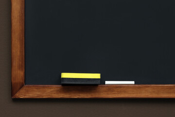 Clean blackboard with chalk and duster hanging on brown wall © New Africa