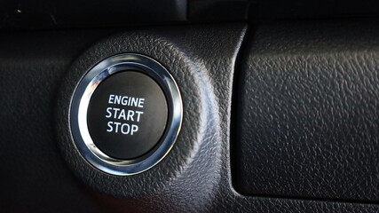 Engine Start Stop button on a car. Closeup of manual car operation button on black dashboard background with copy space. Selective focus