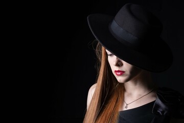 portrait of a girl with long hair, wearing a hat, on a black background