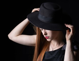 Fototapeta na wymiar portrait of a girl with long hair, wearing a hat, on a black background