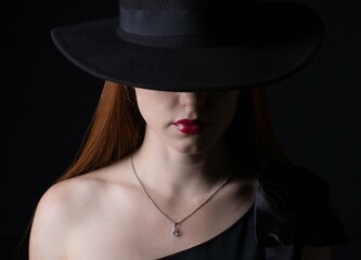 portrait of a girl with long hair, wearing a hat, on a black background