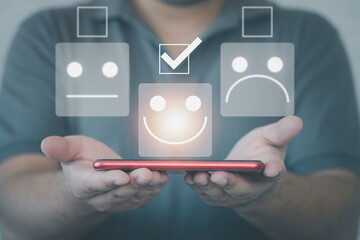 Man showing smartphone choosing happy smiley face icon. Feedback rating