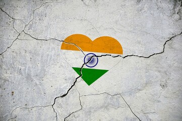 The symbol of the national flag of India in the form of a heart on a cracked concrete wall.