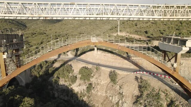 Backward flying motion video revealing the unfinished concrete structure of a bridge under construction in Morella, Spain