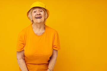 Portrait of an old friendly woman in casual t-shirt yellow panama cropped view
