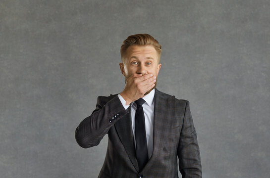 Half-length portrait of surprised businessman entrepreneur wearing formal suit and tie covering mouth with hand palm looking at camera showing amazement, shock emotion keeping secret or saying oops