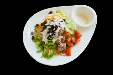 Die cut of Tuna Salad with mixed vegetable on white plate on black isolated.