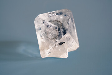Natural crystal of the mineral raw diamond on a blue background