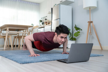 Asian handsome active young man doing push up on floor in living room.