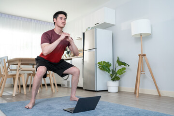 Asian young handsome man doing cardio exercise in living room at home. 