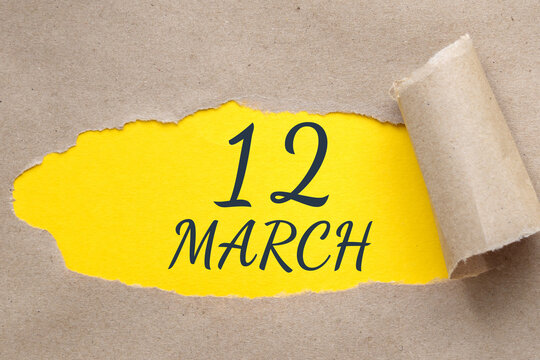 march 12. 12th day of the month, calendar date. Hole in paper with edges torn off. Yellow background is visible through ragged hole.Spring month, day of the year concept