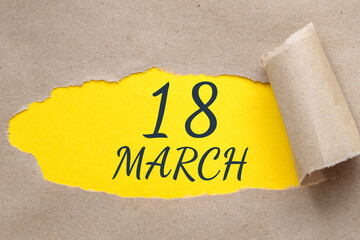 march 18. 18th day of the month, calendar date. Hole in paper with edges torn off. Yellow background is visible through ragged hole.Spring month, day of the year concept